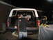 1978 Ford Bronco - Person cleaning out the bed of a 1978 Ford Bronco with a white camper shell at night.