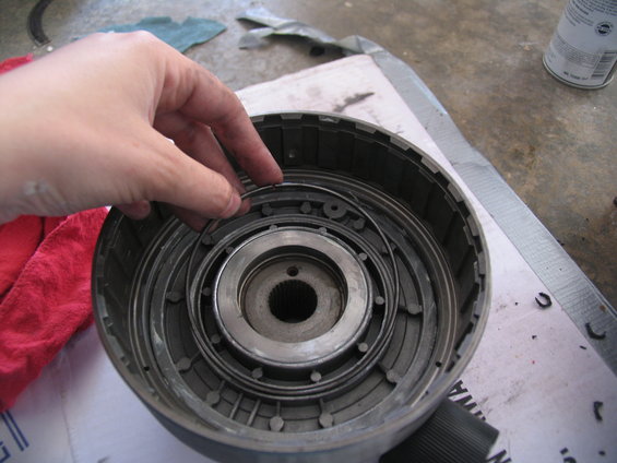 Hand holding a metal ring inside a disassembled transmission drum