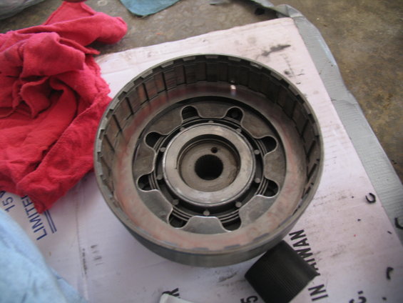 Transmission clutch drum with internal springs and metal plates. Red cloth and paper are nearby