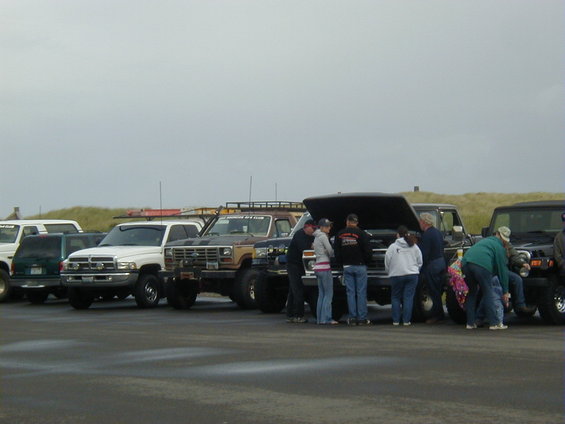 Several trucks and SUVs parked, some with hoods open