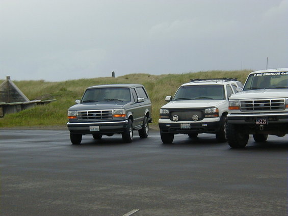 Gray Ford Bronco parked on wet asphalt, front grille and headlights visible