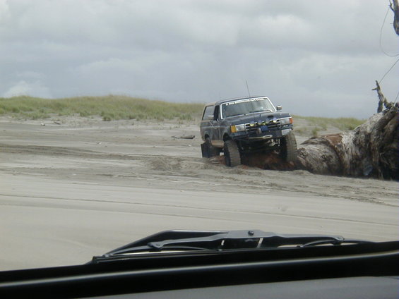 Dark blue SUV with off-road tires and lights on a sandy beach