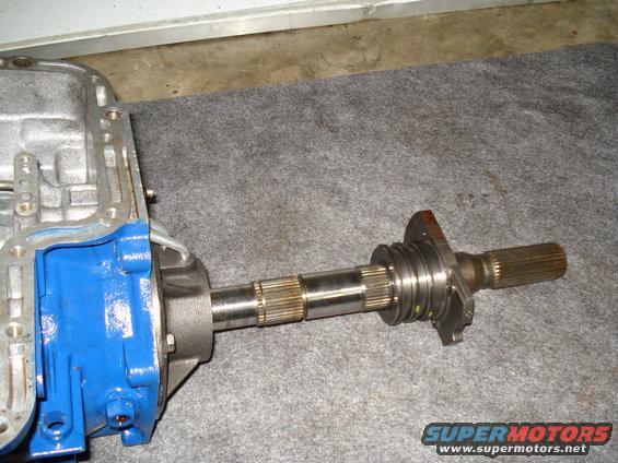 Transmission output shaft with splines and a flange, attached to a blue and silver transmission housing