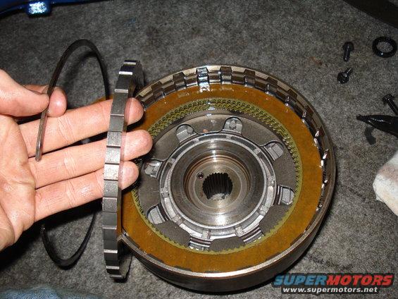 hand holding a metal ring over a transmission clutch pack