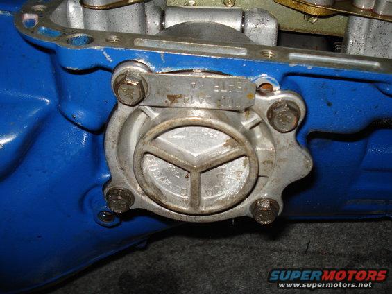 Close-up of a metal transmission part with bolts and stamped numbers