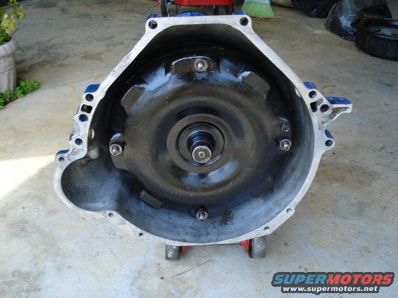 Transmission bell housing with torque converter visible inside, mounted on red dollies