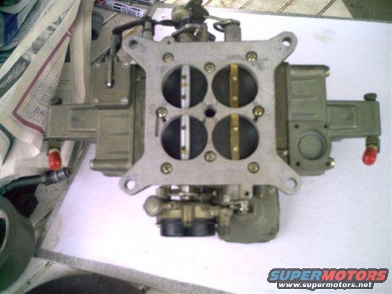 Holley carburetor with four barrels, metal construction, and red fuel line fittings