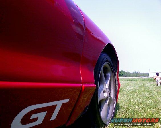 red car side view, showing wheel and GT decal on lower body panel