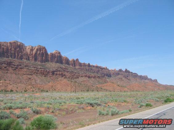 Desert mountains under a blue sky with a road in the foreground
