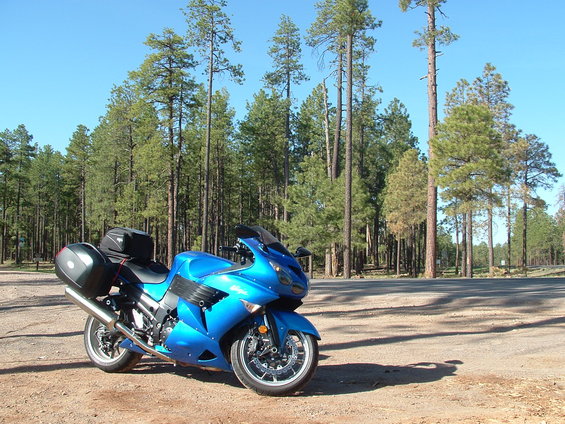 Blue 2007 Kawasaki Ninja motorcycle with black saddlebags parked on a dirt road