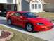 1994 Dodge Stealth - A red sports car is parked in a driveway in front of a house, with an American flag hanging in the open garage.