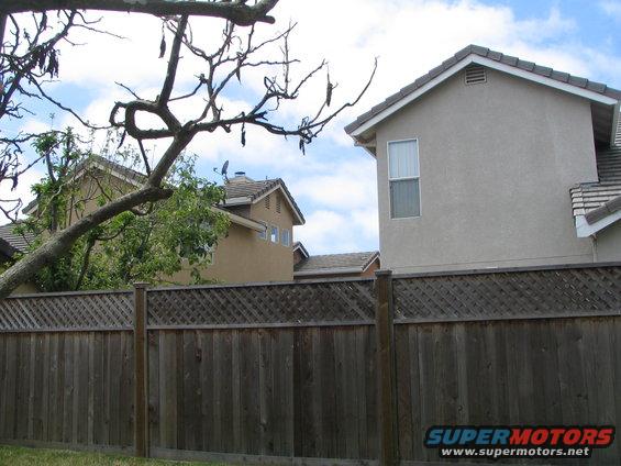 Wooden fence in front of houses under a cloudy sky