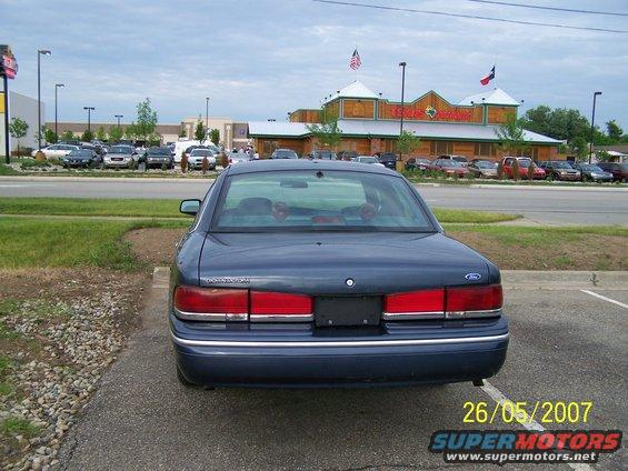 Rear view of a dark blue 2003 Ford Crown Victoria parked in a lot with a restaurant in the background