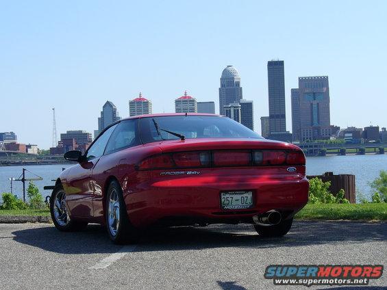 Red 1991 Ford Probe 24v parked with Louisville skyline in background