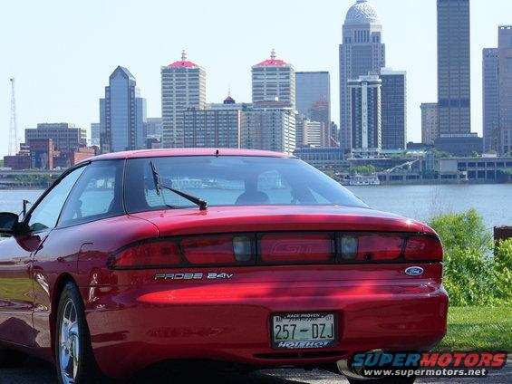 Red Ford Probe GT with a GT badge on the rear, parked with a city skyline in the background