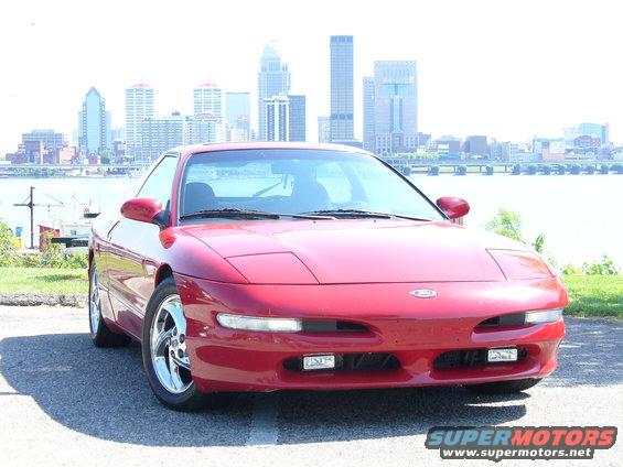 Red 1991 Ford Probe front view with city skyline