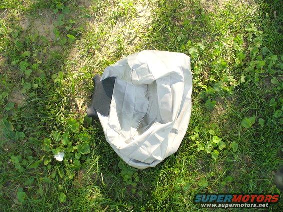 car cover lying on grass, with a dark piece of trim visible