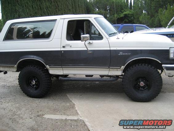 Two-tone white and dark gray Ford Bronco with aftermarket wheels and tires, side view