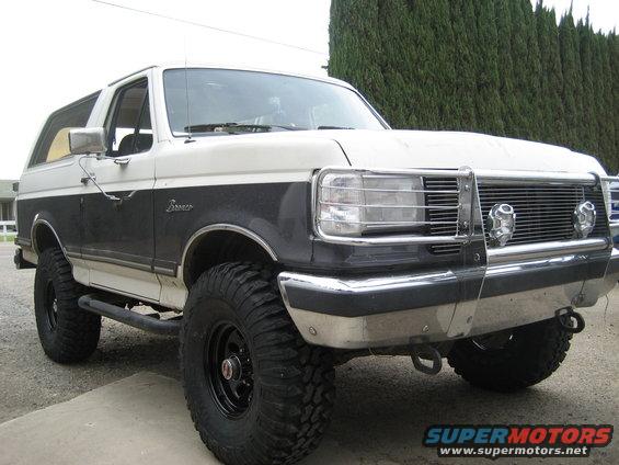 1989 Ford Bronco, two-tone white and dark gray, with large off-road tires and a chrome grille guard
