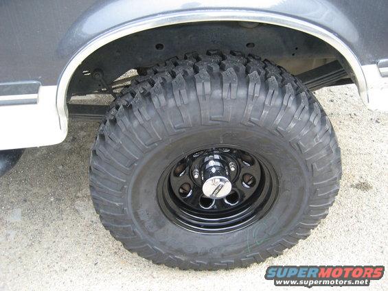 Close-up of a large off-road tire on a black rim, showing the rear wheel well and part of the vehicle's body