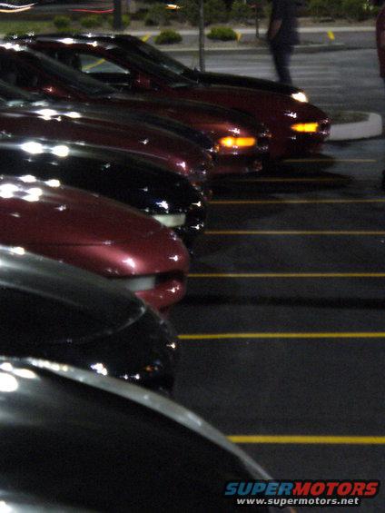 Several cars parked side-by-side, one red, others black