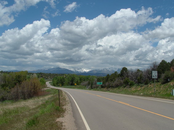 Road leading to snow-capped mountains under a cloudy sky