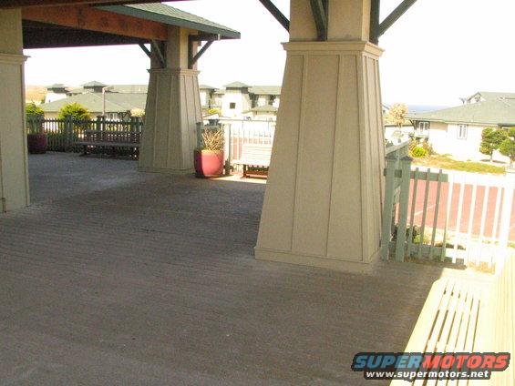 Covered porch with pillars, benches, and a view of buildings and the ocean