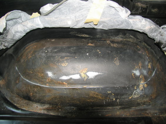 close-up of a rusty, dirty wheel well interior with some white primer patches