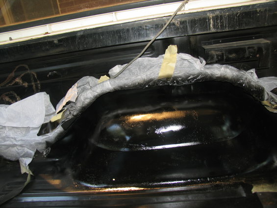 Black painted wheel well covered with masking tape and paper