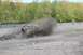 1991 Ford Bronco - A yellow Jeep Wrangler navigates a muddy obstacle, sending dirt and debris flying.
