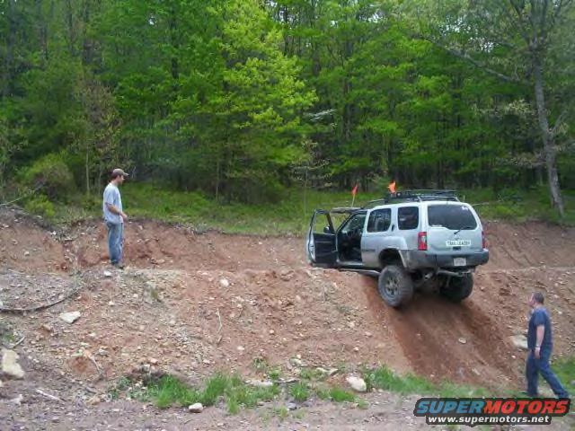 Silver SUV with doors open on a steep dirt incline, two men nearby
