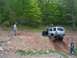 1991 Ford Bronco - A silver SUV navigates a challenging dirt hill with two men observing the off-road activity.