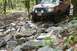 1991 Ford Bronco - Off-roading SUV tackles a challenging, boulder-strewn path in a wooded area.