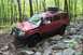 1991 Ford Bronco - This red SUV is equipped for off-road adventures, tackling a challenging rocky path in a wooded area.