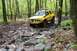 1991 Ford Bronco - A yellow SUV navigates a challenging rocky path through a dense forest.