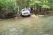 1991 Ford Bronco - A 1991 Ford Bronco navigates a rocky stream bed surrounded by trees.
