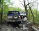 1991 Ford Bronco - A 1991 Ford Bronco navigates a challenging off-road trail, with another SUV visible in the background.