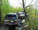 1991 Ford Bronco - Two SUVs navigate a challenging off-road path, with one Ford Bronco loaded for an adventure.
