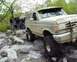 1991 Ford Bronco - A group of people are gathered around two off-road vehicles on a rocky, wooded trail.