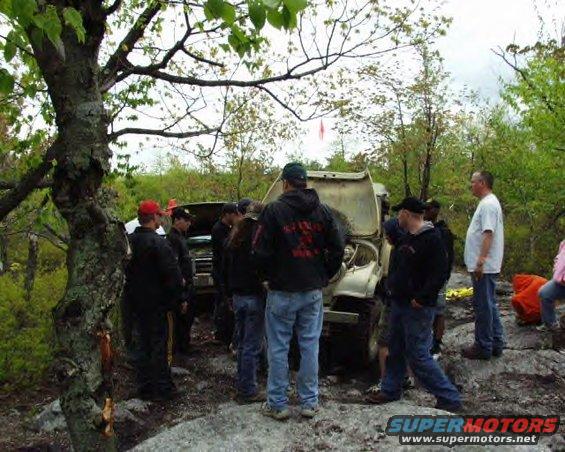 1991 Ford Bronco with hood open, surrounded by people in a wooded area