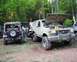 1991 Ford Bronco - A white 1991 Ford Bronco with its hood open is parked in a wooded area next to a Jeep and other vehicles.