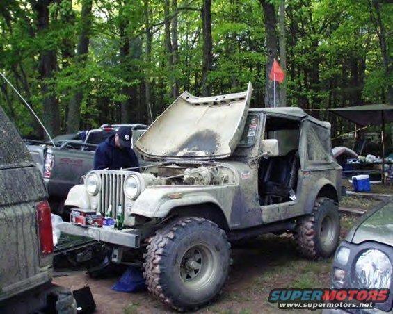 Camouflaged Jeep CJ-7 with hood open, parked outdoors