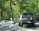 1991 Ford Bronco - A Ford Bronco navigates a rocky, wooded trail during the daytime.