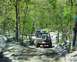 1991 Ford Bronco - A convoy of Ford Broncos navigates a challenging off-road trail through a dense forest.