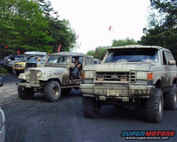 Muddy Ford Bronco and Jeep CJ parked on dirt road. Bronco has "FRIENDS IN LOW PLACES" text above grille