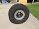 1983 Ferrari Enzo - A large, aggressive off-road tire is mounted on a silver beadlock wheel, resting on a concrete surface.