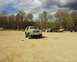 1991 Ford Bronco - A 1991 Ford Bronco is parked in a dirt lot alongside other off-road vehicles under a cloudy sky.