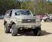 1991 Ford Bronco - Mud-covered 1991 Ford Bronco parked at an outdoor event with other vehicles present.