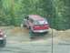 1991 Ford Bronco - A red Dodge SUV navigates a steep dirt incline during an off-road excursion, with a red Jeep partially visible.