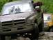 1991 Ford Bronco - Muddy Dodge Ram truck navigating rocky terrain with another vehicle in the background.